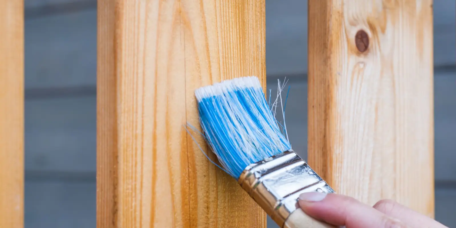 A brush putting stain on a wood fence