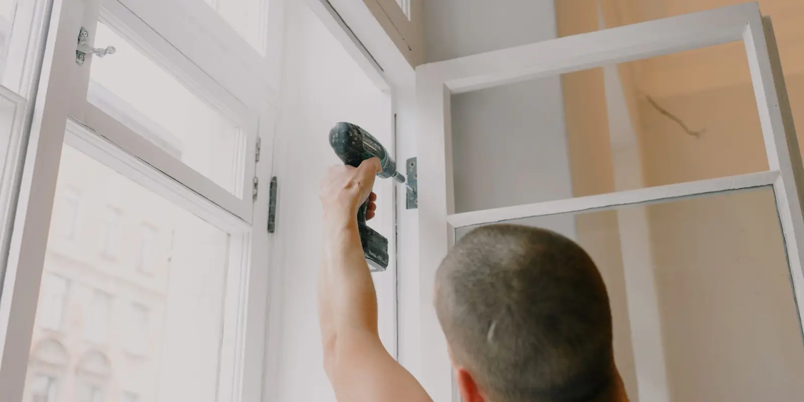 A man drilling a hinge on a door