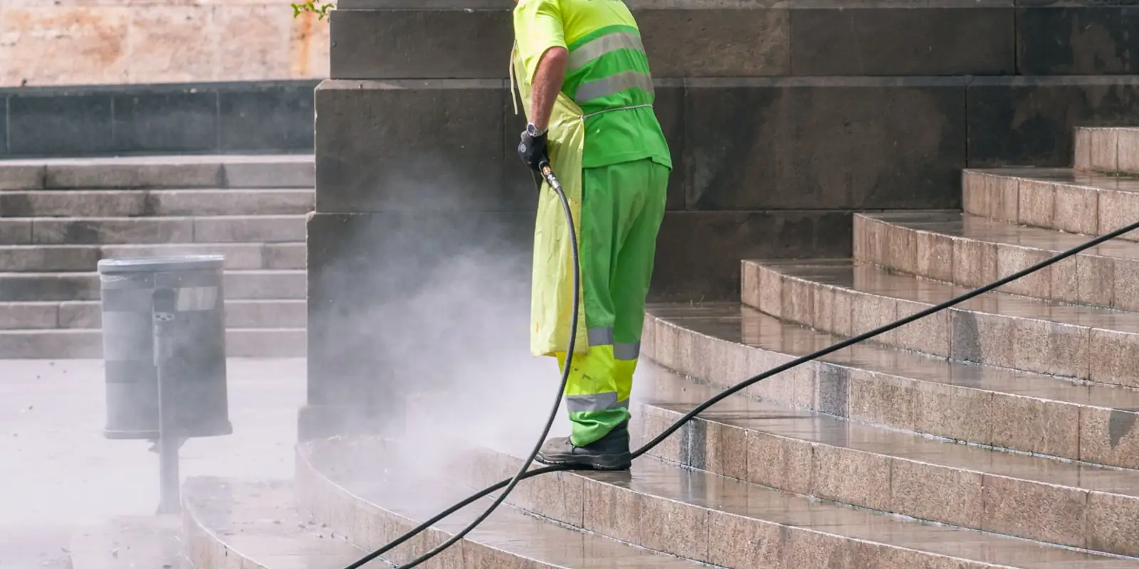 A worker pressure washing stone steps