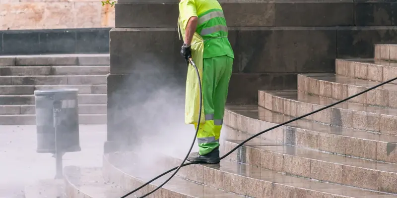 A worker pressure washing stone steps