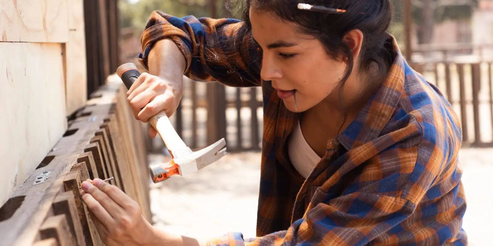A woman hammering a fence board into place