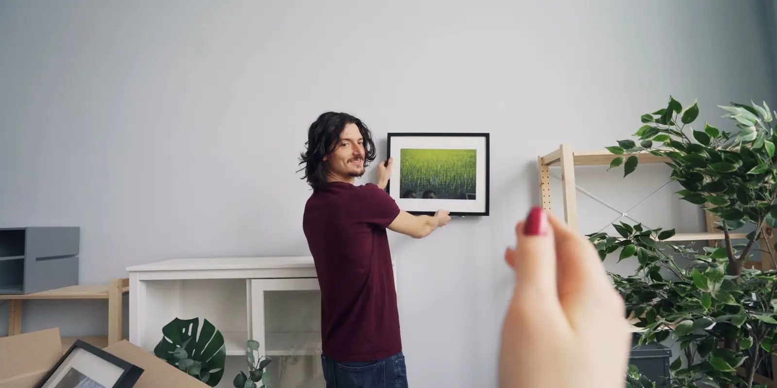 A man hanging a picture on the wall