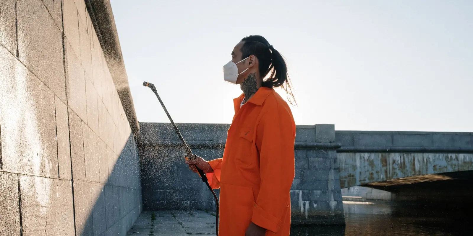 A worker pressure washing an outside wall