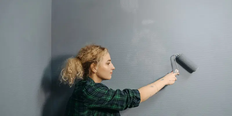 A woman rolling paint onto a wall