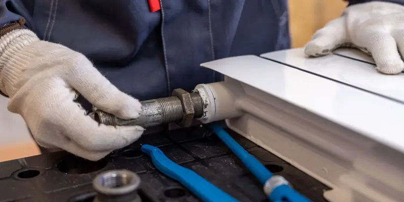 Gloved hands fitting a pipe under a sink