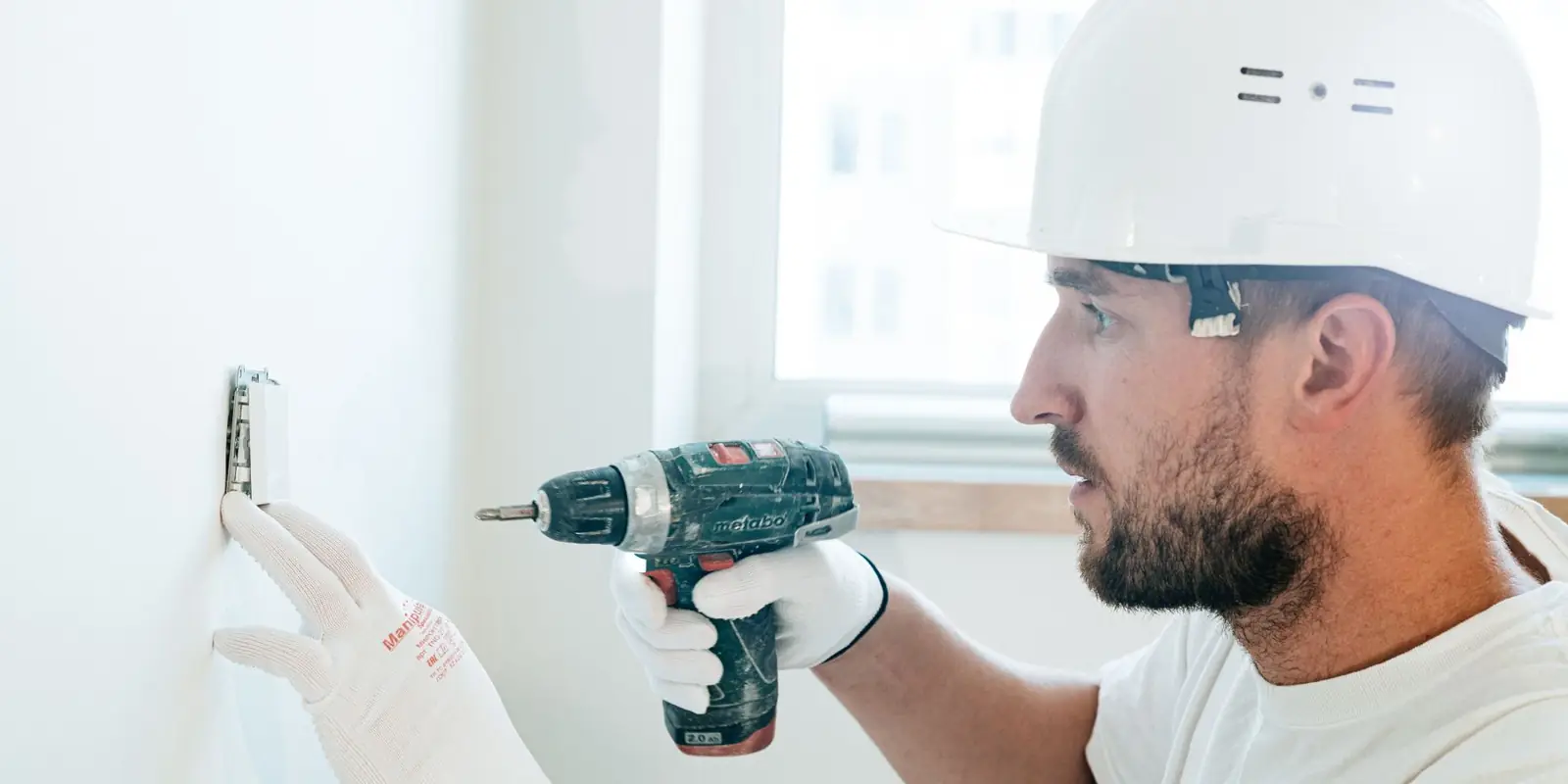 A tradesman drilling into a wall to put up a mount