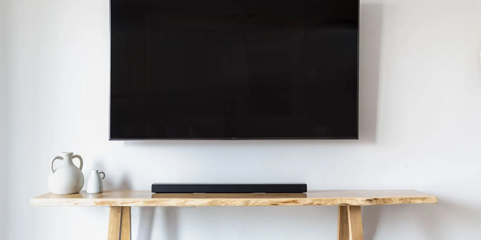 A wall-mounted TV with a soundbar on the console below
