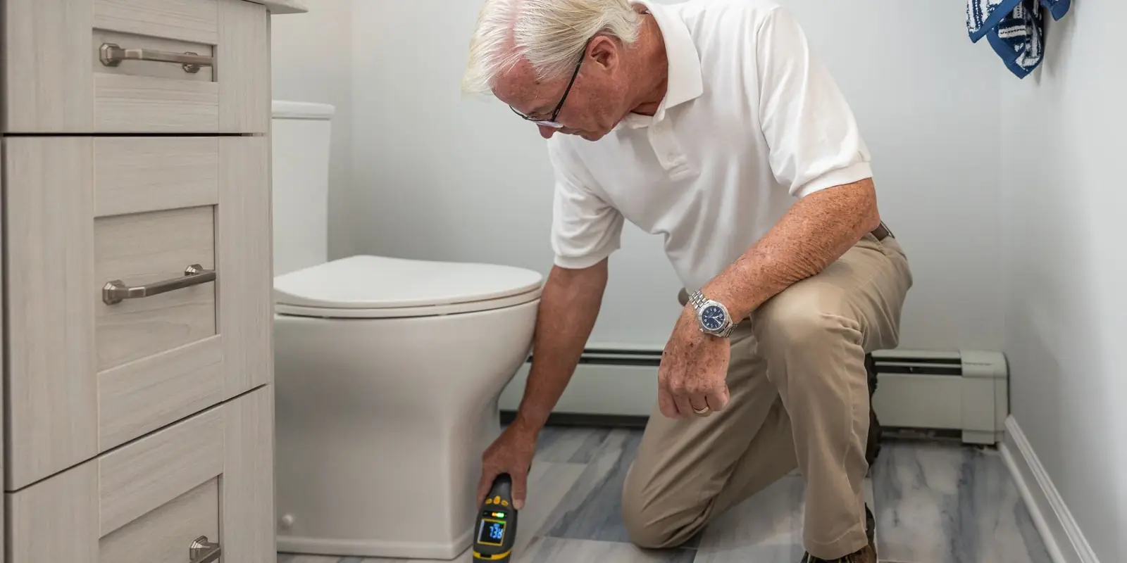 A man kneeling to work on a toilet