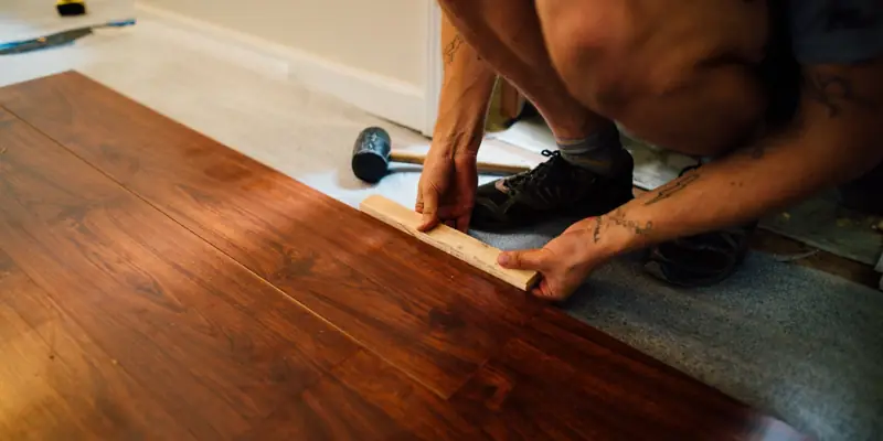 Hands laying a plank of new flooring